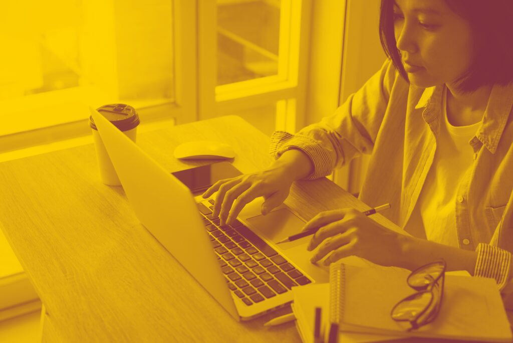 Woman sitting at a desk and typing on a laptop.