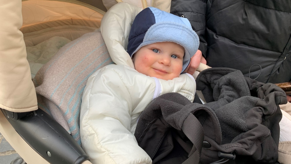 Infant in a thick jacket and wrapped in blankets sits in a stroller.