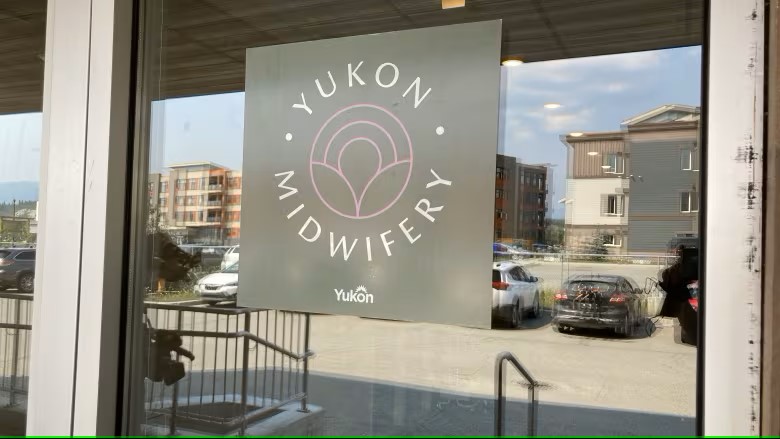 The image shows the entrance of a building with a sign on the glass door that reads 